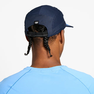 back view of the ciele athletics GOCap unisex running hat in indigo color, on a model