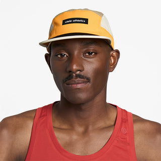 front view of ciele athletics GOCap Field Iconic Bar unisex running hat in clementine sand color on a model