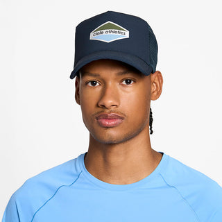 front view of the ciele athletics TRLCap unisex running hat with a curved brim in deep space color, on a model