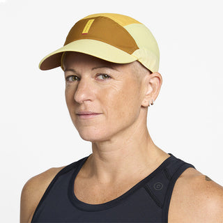 side view of ciele athletics FSTCap SC Comp Iconic VC unisex running hat in dark ochre sulfur color on a model