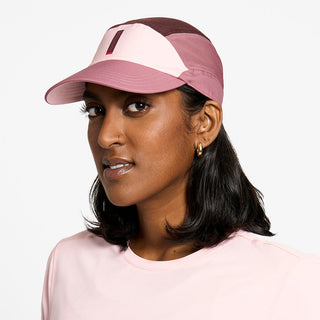 side view of the ciele athletics FTSCap unisex running hat with a curved brim in peachskin color, on a model