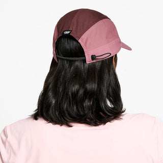 back view of the ciele athletics FTSCap unisex running hat with a curved brim in peachskin color, on a model