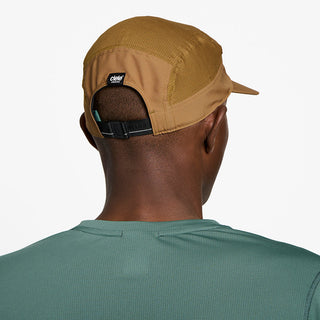 back view of ciele athletics GOCap Comp Bars unisex running hat in dark ochre color on a model