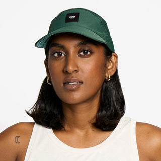 side view of the ciele athletics FTSCap unisex running hat with a curved brim in emerald color, on a model