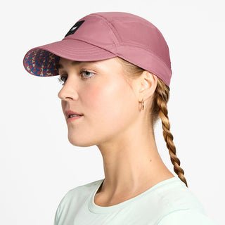 side view of the ciele athletics FTSCap unisex running hat with a curved brim in deco rose color, on a model