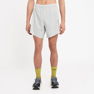 person wearing light gray athletic shorts and green socks on a white background